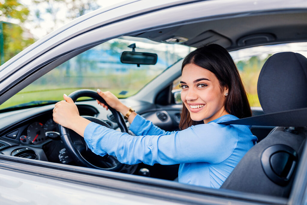jeune femme brune souriante au volant de sa voiture prend la route tranquillement Mutuelle Générale Avignon